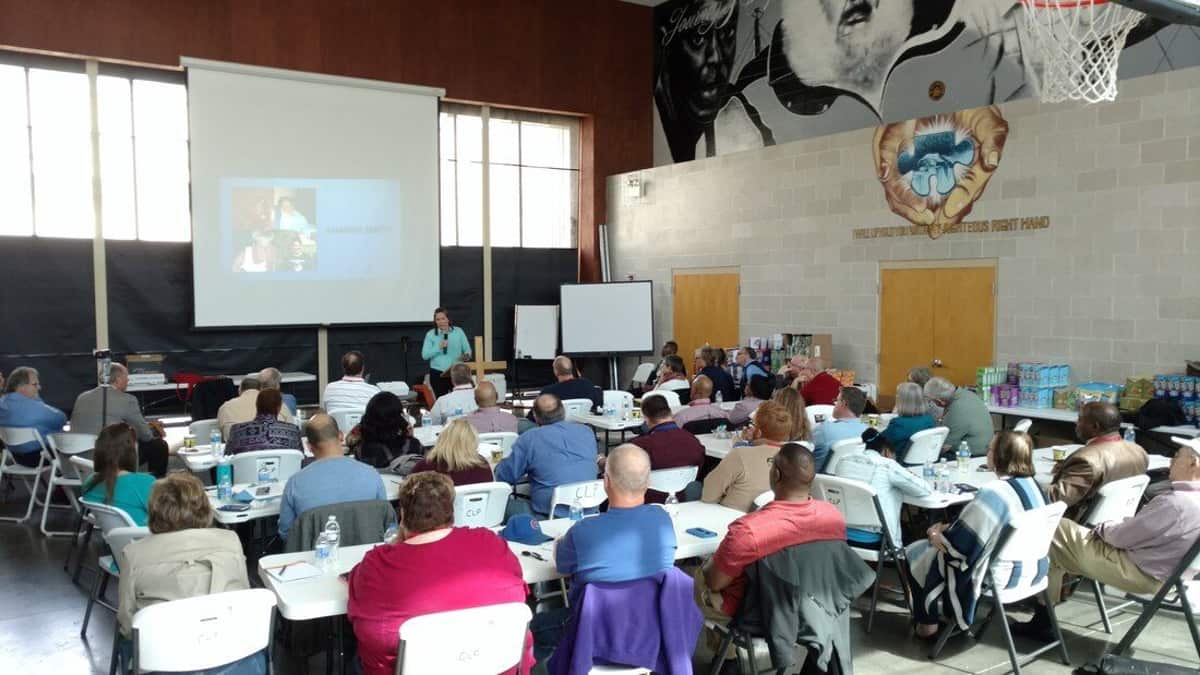 Rescue mission staff at round tables watching a presentation, spring 2018 in Kansas City