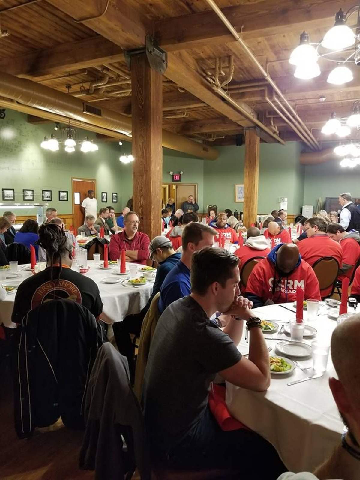 Conference guests seated at long dinner tables in a timber-beamed hall, fall 2018