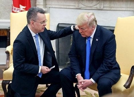 Dr. Andrew Brunson kneeling in prayer beside President Donald Trump